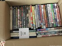 Top view of a large box filled with DVD movies placed vertically showing titles on the spine.