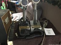 Photo of three used microphones on bases with coiled cables