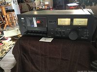 Full front view of the Sansui D-90 cassette deck showing cassette compartment, VU meters, control buttons, and dials.