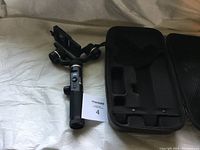 FeiyuTech camera stabilizer next to its custom foam fitted carrying case, showing the stabilizer handle with buttons and mount.