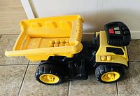 Side view of 3 in 1 ride on truck with dumping bed lowered and remote control on top.