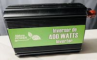 Black Nature Power 400 watts power inverter with green label visible and red connector on side.