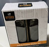 Photo of the unopened box containing salt and pepper shaker set from Kitchen Creation, showing front view with branding and packaging details.