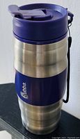 Photo showing Bubba thermos travel mug in stainless steel and blue with carry strap and flip lid.