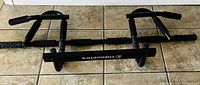 Full view of black metal Energetics push up bar on tiled floor.