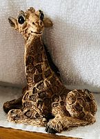 Close-up of a seated giraffe decor figurine showing detailed texture and painted spots.