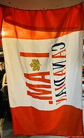 Photo of a fabric flag with red borders and white middle section. Text 'I AM CANADIAN' and a gold maple leaf are visible.