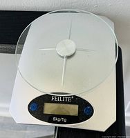 Top view of FEILITE digital kitchen scale showing glass weighing platform, digital screen, and buttons.