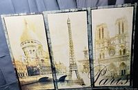 Photo showing three vertical canvas art panels of Paris landmarks with sepia tone and vintage style.