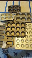 All 7 baking muffin tins laid out on table, showing variety in sizes and styles.