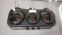 Front view of the triple slow cooker unit with three crockpots and glass lids.