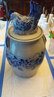 Photo showing full crock with floral decoration and blue chicken lid from above angle