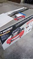 Original box packaging of Husky air compressor with product information and specifications visible.