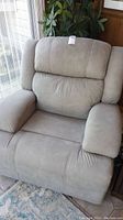 Frontal view of a gray upholstered reclining chair showing padded backrest and armrests.