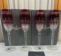 Four ruby red hock glasses displayed with original Waterford Crystal boxes and branded booklet