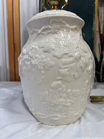 Close-up of the white Belleek Parian china lamp body showing detailed raised floral and leaf patterns and glossy finish.