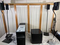 Full system overview showing two satellite speakers on stands and two Acoustimass bass modules, one rectangular with label, one cube-shaped with glossy finish