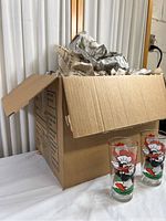 Box filled with newspaper packing and multiple Looney Tunes Pepsi collector glasses featuring Daffy Duck character visible outside box.