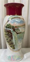 Front view showing scenic painted illustration of Niagara Falls on white iridescent porcelain with red rim and gold detail
