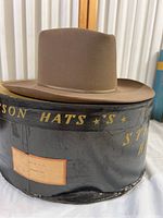 Side view of brown Stetson felt hat on original black Stetson box showing box wear.