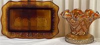 Photo of amber glass rectangular Last Supper plate and ruffled-edge decorative dish side by side on a white surface.