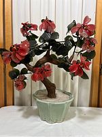 Front view of vintage artificial bonsai with red flowers and green leaves in a light green ceramic pot.