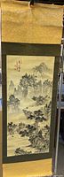 Full view of the vintage Asian scroll showing black and white landscape painting with mountains and trees.