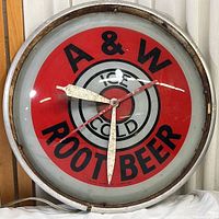 Full front view of the vintage A & W Root Beer wall clock showing branding, clock hands and metal rim.