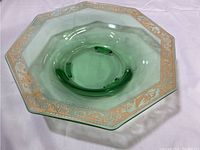 Top-down angled view of the octagonal green glass dish with gold trim, showing shape, color, and wear on the gold.