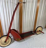 Full view of the vintage red Jamestown Croft scooter showing the entire side profile and structure with two cream-colored wheels.