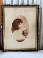 Full view of the framed vintage print with ornate black and gold frame, showing some damage.