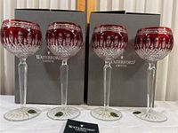 Four ruby and clear crystal glasses displayed in front of original Waterford boxes
