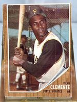 Close-up photo of the front of the 1962 Topps Roberto Clemente baseball card showing player preparing to bat with a baseball bat, wearing Pittsburgh Pirates uniform and cap.