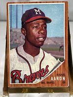 Front view of the 1962 Topps #320 Hank Aaron Milwaukee Braves baseball card showing the player in uniform with a wooden panel background design.