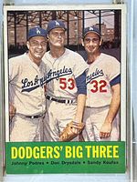 Front color photo of 1963 Topps Dodgers Big Three card showing players Johnny Podres, Don Drysdale, and Sandy Koufax in Los Angeles uniforms with green and yellow text banner below.