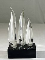 Front view of crystal art glass penguins sculpture on black lucite base