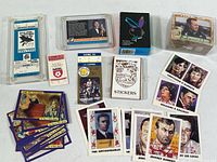 Overview photo showing multiple item groups including framed hockey ticket, sports tickets, various trading cards themed on crime, sports, and historical events, and boxed sticker sets