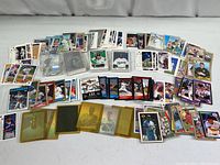 Wide view of mixed baseball cards spread out showing different teams and player cards from the late 1980s and early 1990s in various conditions with some protective sleeves.