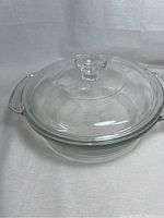 Clear glass round casserole dish with lid on top against white background