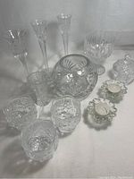 Overview of the cut crystal collection showing various candle holders, vase, and jar against a white background