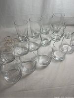 Group photo of 9 clear glasses arranged on a neutral background, including tall glasses, short tumblers, and small glasses with gold rims.