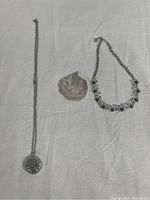 Full lot of two necklaces and one pendant displayed on a white fabric background