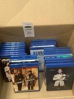 Box containing multiple Blu-ray movie cases in blue with some visible titles including Donnie Brasco and Mamma Mia!