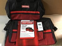 Two Craftsman tool bags, one 13 inch and one 18 inch black with red mesh exterior pockets, labeled with product card showing brand and size.