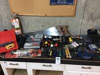 Wide view of all tools on black countertop showing saw, screwdrivers, chisels, drill, level, and cases.