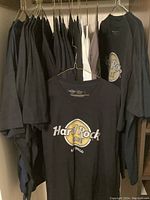 Black crew-neck tee with yellow and white Hard Rock Cafe San Diego logo hanging in a row of dark shirts