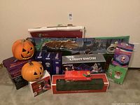 Photo showing two plastic jack-o'-lantern pumpkins, boxed seasonal light kits, lighted garland box, and light show kits.