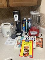 Photo showing KitchenAid blender, SodaStream machine with new bottles, rice cooker, and four cookbooks