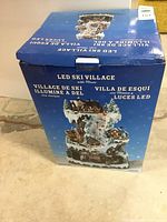 Box of LED Ski Village Christmas display with music, showing product branding and condition details.
