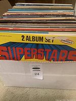 Front view of the box containing multiple vinyl LP records packed vertically showing a partial view of an album with 'Superstars' in large colorful font, and a yellow 2-album set band.
